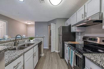 An open kitchen with granite counter tops and stainless steel appliances